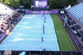 Staff covers the tennis court from the rain