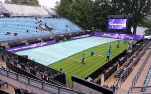 Staff covers the tennis court from the rain