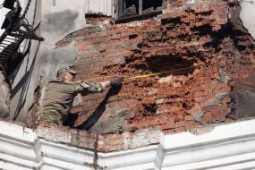 A serviceman takes measurements to record a Russian war crime on the wall of the Assumption Cathedral of the Kyiv Pechersk Lavra