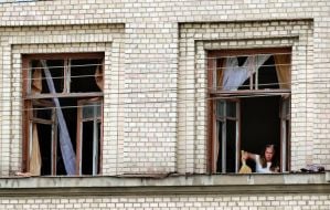 A woman removes broken glass from a window in a building on the territory of the Oleksandr Dovzhenko National Film Studio in Kyiv