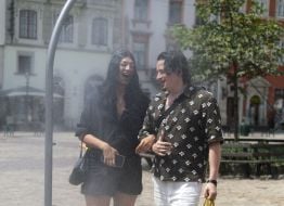 People cool off near street water sprinklers during the intense summer heat in Lviv