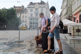 People cool off near street water sprinklers during the intense summer heat in Lviv