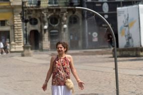 People cool off near street water sprinklers during the intense summer heat in Lviv