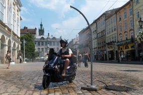 People cool off near street water sprinklers during the intense summer heat in Lviv
