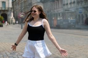 People cool off near street water sprinklers during the intense summer heat in Lviv