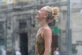 People cool off near street water sprinklers during the intense summer heat in Lviv