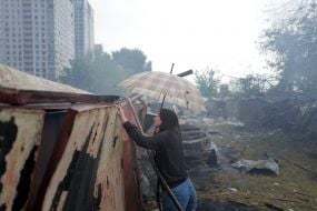 Жінка з парасолею оглядає знищені гаражі на одній з локацій після масованого удару по Києву