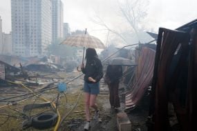 Жінка з парасолею оглядає знищені гаражі на одній з локацій після масованого удару по Києву