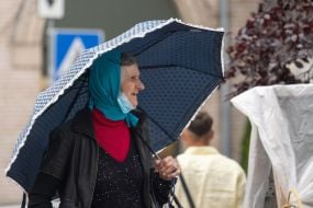 Літня жінка з парасолькою під дощем