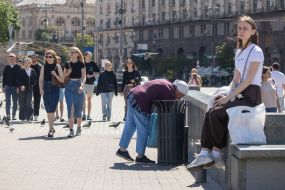 Літня жінка перевіряє смітник у центрі Києва