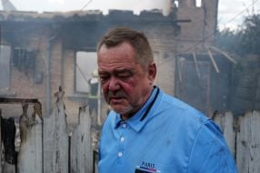 Чоловік на фоні зруйнованого після нічної російської атаки будинку у місті Вишневому