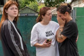 Neighbors comfort a woman who is mourning the death of her loved one after a Russian small-sized cruise missile, Banderol, hit a private home
