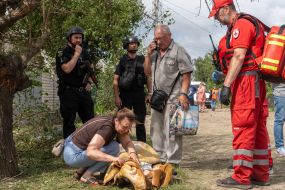 A woman cries near the body of a deceased person after a Russian small-sized cruise missile, Banderol, hit a private house