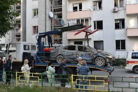 Municipal services evacuate a burned car after a Russian missile hit a residential building in Lviv