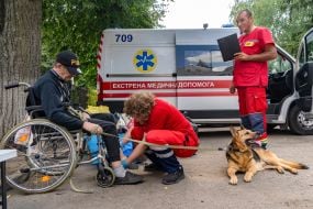 A man evacuated from the Shevchenkivska community of the Kupyanskyi district in a wheelchair with a shepherd dog on a leash at the IDP reception point in Kharkiv