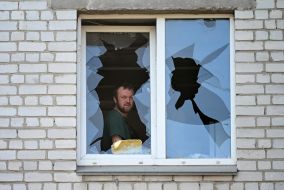 Мужчина смотрит из разбитого в результате массированной комбинированной атаки рф окна в жилом доме в Соломенском районе Киева
