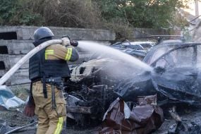 A rescuer extinguishes a fire in a car.