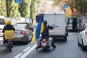 Glovo delivery service courier and a motorcyclist with a Ukrainian flag
