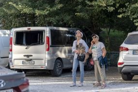 Перехожі розглядають пошкоджену внаслідок обстрілу будівлю