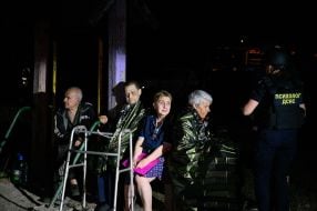 People near a house damaged by Russian shelling