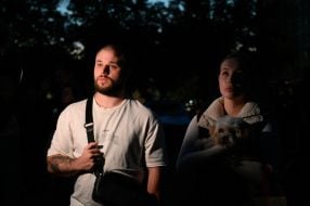 People near a house damaged by Russian shelling