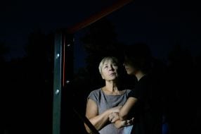 People near a house damaged by Russian shelling