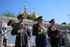 Honor guard soldiers with flowers near the Wall of Remembrance in Kyiv.
