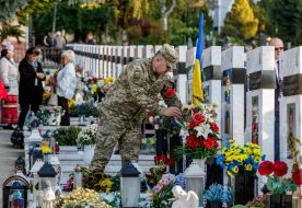 A serviceman lays flowers at the graves of his comrades-in-arms on the Day of Defenders of Ukraine
