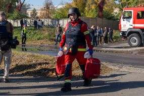 Сотрудница экстренной медицинской помощи возле дома, пострадавшего в результате обстрела РФ