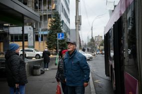People at a bus stop near the Cosmo Multimall shopping center, which was damaged in a Russian attack