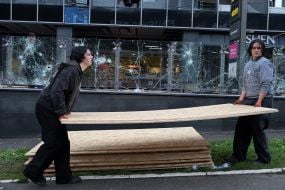 Men are carrying a sheet of plywood