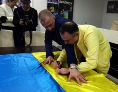 Вадим Гутцайт ставит свой автограф с пожеланиями на флаге
