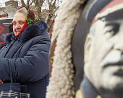 Женщина стоит возле плаката с изображением Сталина во время митинга, посвященного годовщины 89-той годовщине Октябрьской революции. Киев, 7 ноября