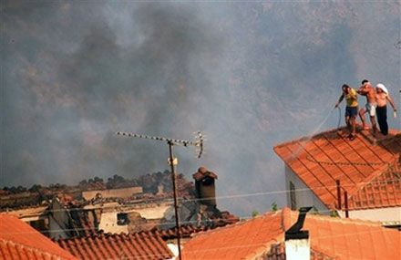 Жители с. Маврики на юге Греции поливают водой крыши своих домов. (AP Photo)