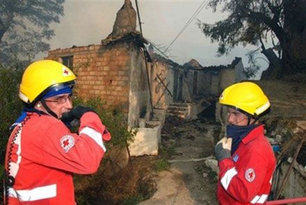 Спасатели перед сгоревшим домом в с. Маврики на юге Греции. (AP Photo)