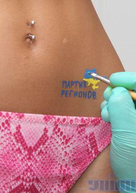 Художник прикрашає сіднички моделі партійним логотипом (фоторепортаж)