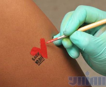 Художник прикрашає сіднички моделі партійним логотипом (фоторепортаж)