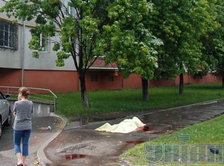 Женщина стоит возле накрытого простыней тела пострадавшего от урагана во Львове  23 июня