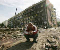 Літній чоловік присів посеред зруйнованої вулиці у місті Горі (Грузія). 11 серпня