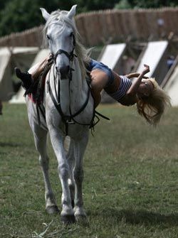 Девушка демонстрирует  трюк, сидя верхом на коне, во время фестиваля каскадеров