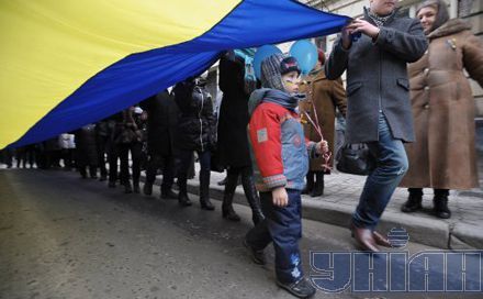 Участники торжественного вече во Львове несут большой флаг Украины