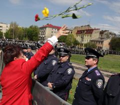 Жінка, яка не змогла пройти до могил радянських воїнів, кидає квіти на могили через міліцейський кордон 