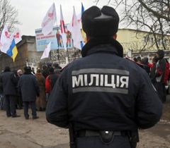 Милиционер стоит возле участников митинга в поддержку Юлии Тимошенко возле Качановской колонии