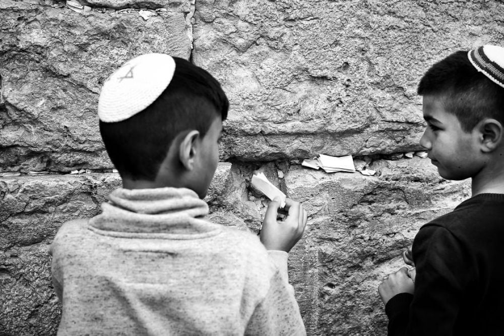 Дети засовывают записки с просьбами и молитвами между камней Стены Плача