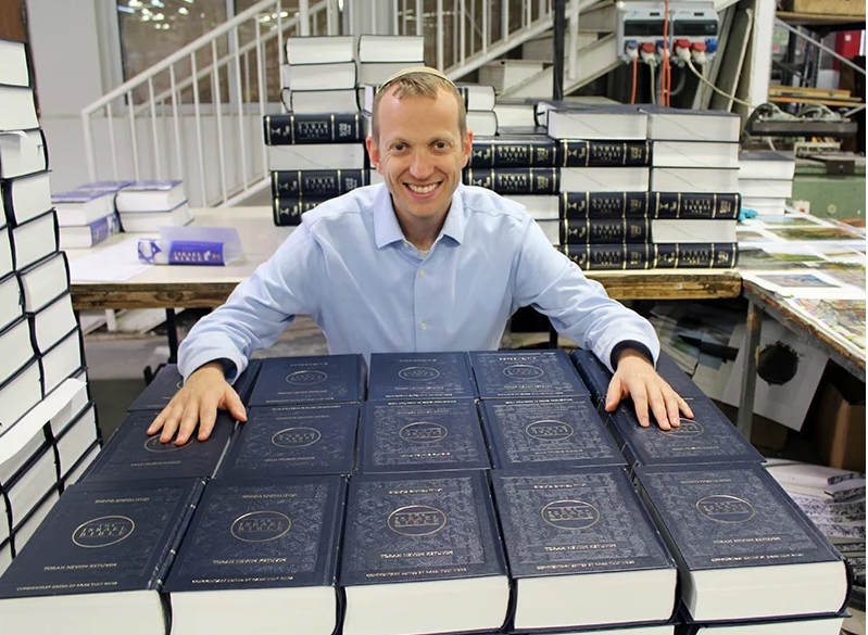 Раввин Тули Вайс со стеками Библии Израиля, которую он редактировал. Фото предоставлено Israel365
