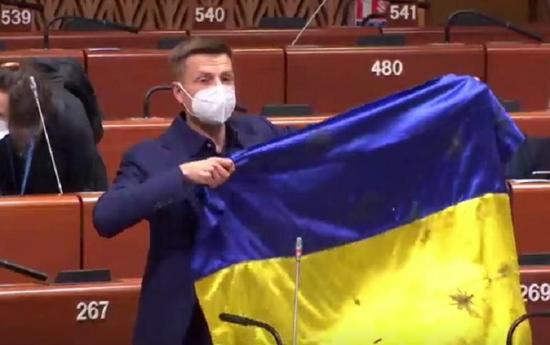 Гончаренко на открытии весенней сессии ПАСЕ продемонстрировал простреленный в ООС флаг / Скриншот Гончаренко на открытии весенней сессии ПАСЕ продемонстрировал простреленный в ООС флаг / Скриншот