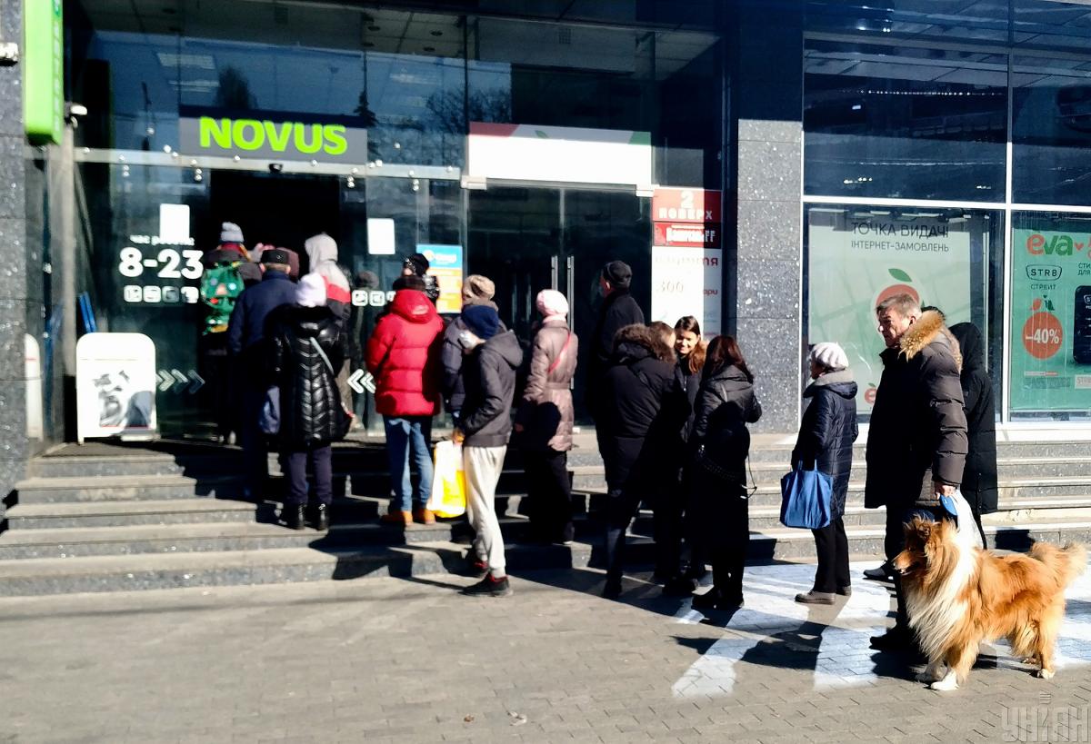 Люди стоять в черзі біля магазину NOVUS на Львівській площі в Києві / фото Александр Синица Люди стоять в черзі біля магазину NOVUS на Львівській площі в Києві / фото Александр Синица