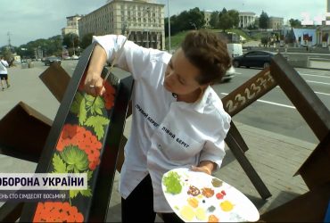 Художница расписывает противотанковые ежи петриковской росписью