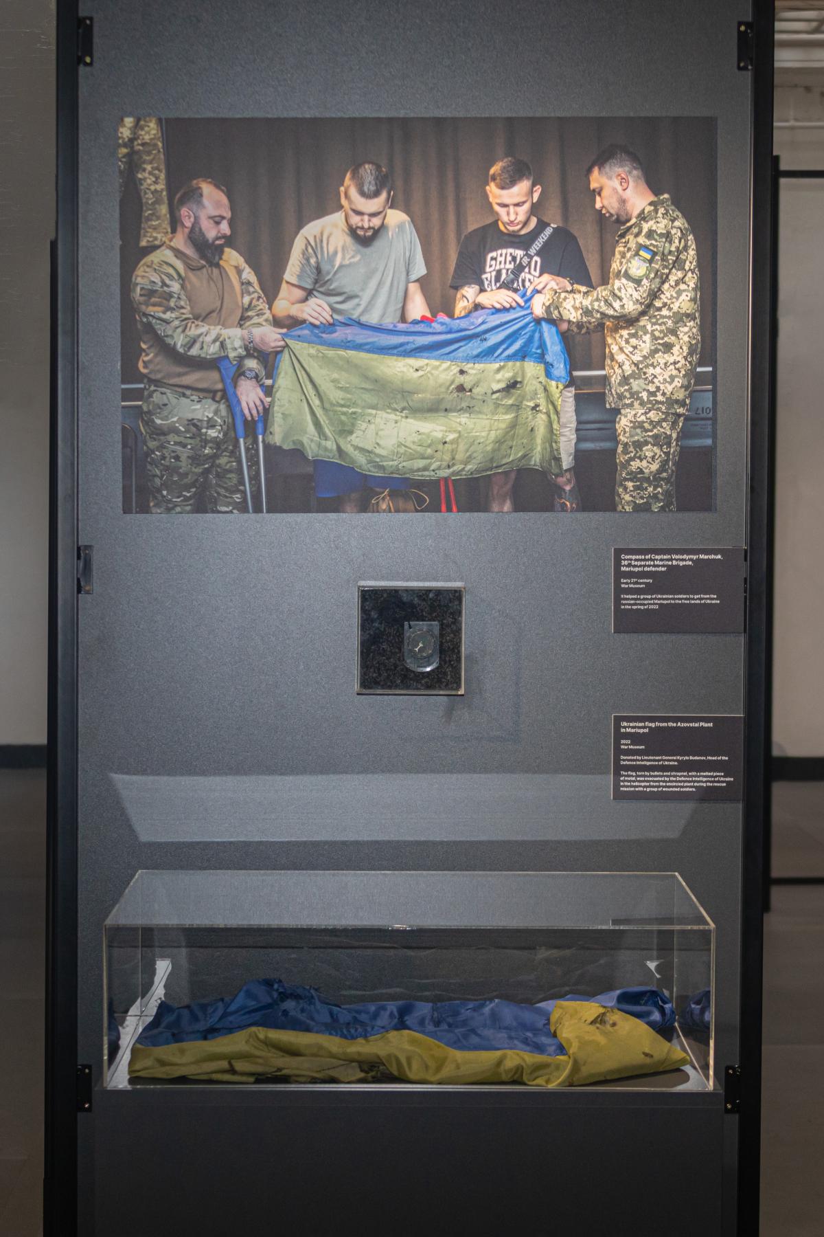 Среди экспонатов - флаг Украины, спасенный с завода "Азовсталь" и вывезенный вертолетом во время военной операции, который символизирует несокрушимость украинского народа Среди экспонатов - флаг Украины, спасенный с завода "Азовсталь" и вывезенный вертолетом во время военной операции, который символизирует несокрушимость украинского народа